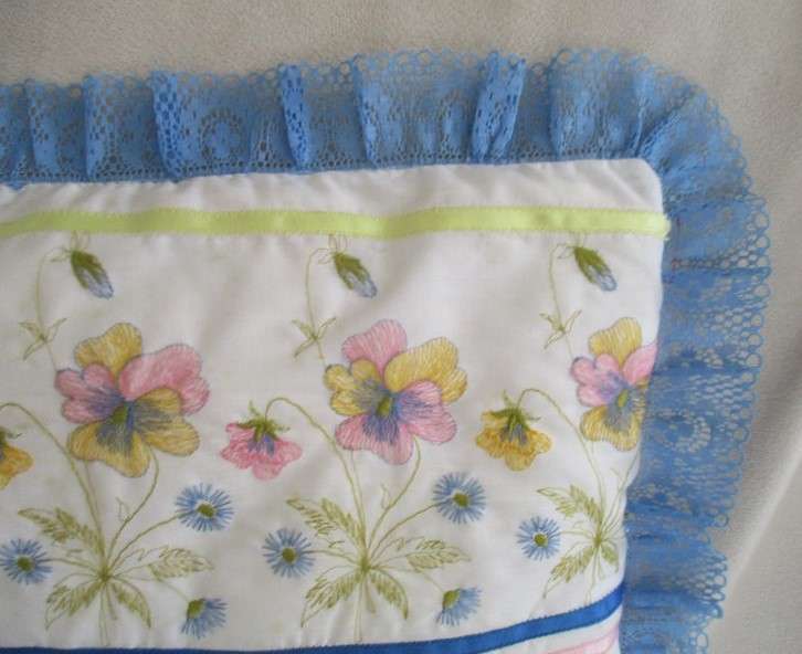 A pretty cushion with dainty embroidery and lace border