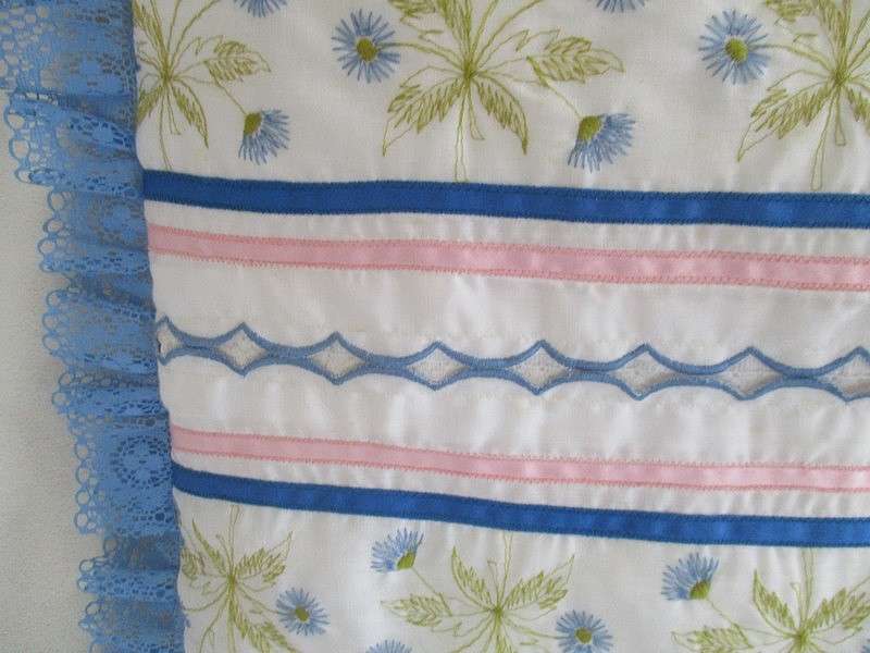 A pretty cushion with dainty embroidery and lace border