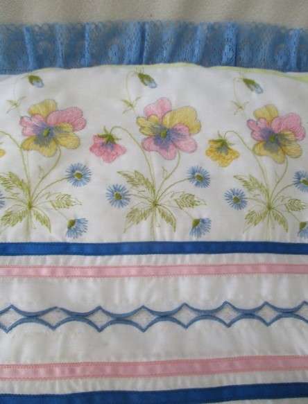 A pretty cushion with dainty embroidery and lace border