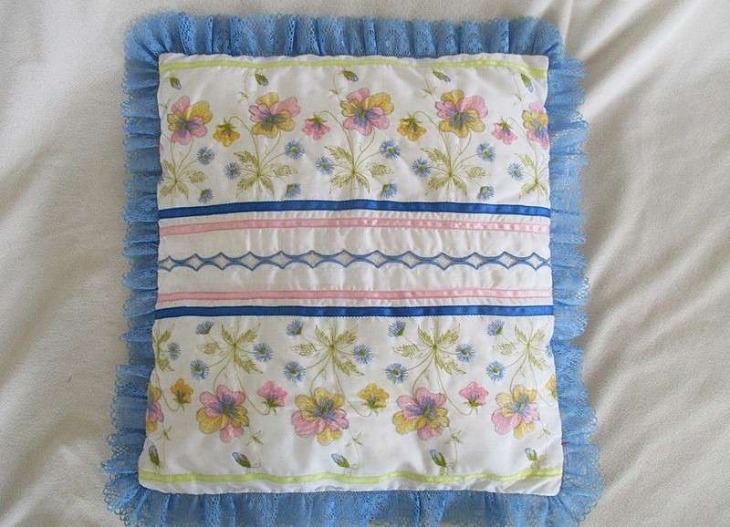 A pretty cushion with dainty embroidery and lace border