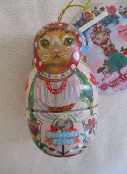 A cute Matryoshka nesting doll-shaped novelty kitty tin with tube of unused hand cream