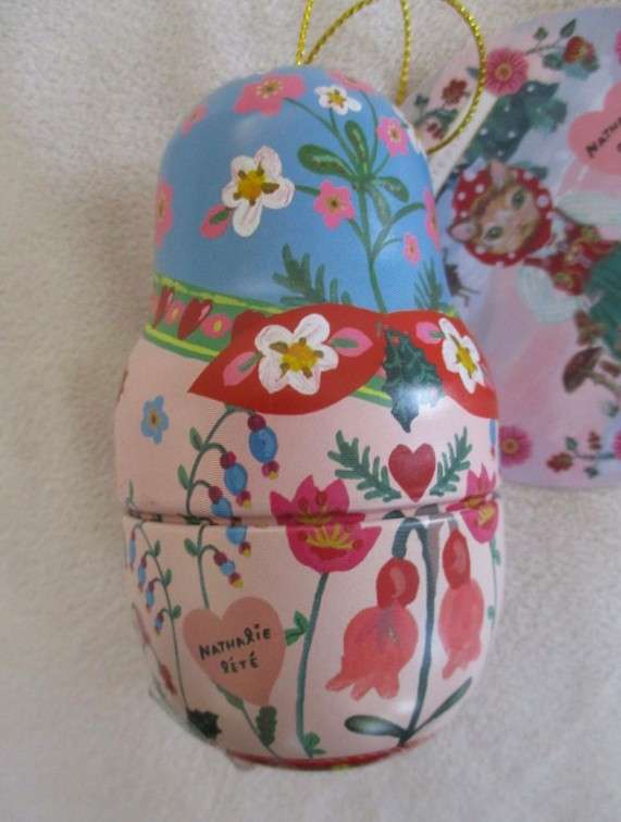A cute Matryoshka nesting doll-shaped novelty kitty tin with tube of unused hand cream