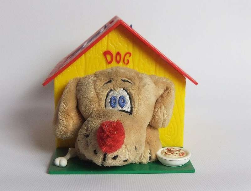 A hardened plastic dog kennel and plush dog ornament or toy made in the Netherlands for Vero sweets