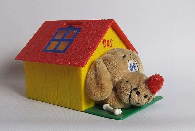 A hardened plastic dog kennel and plush dog ornament or toy made in the Netherlands for Vero sweets