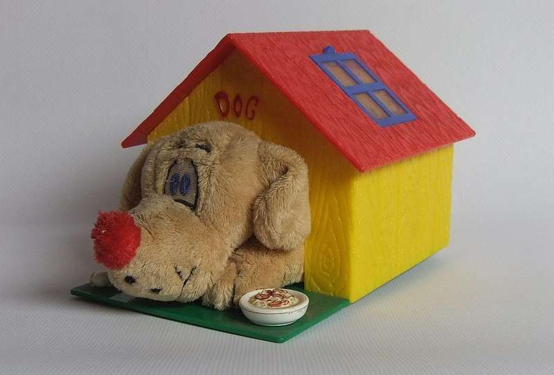 A hardened plastic dog kennel and plush dog ornament or toy made in the Netherlands for Vero sweets