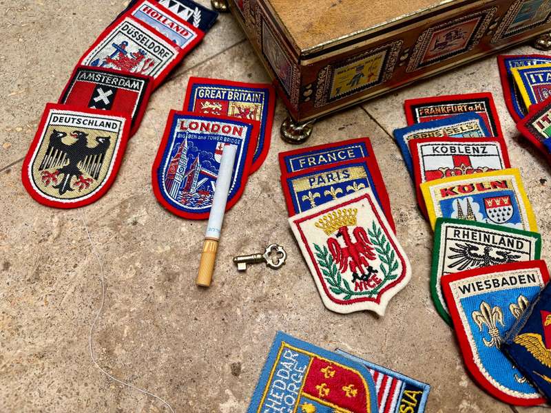 Stamp collector footed tin box with 25 travel badge lot Europe badges