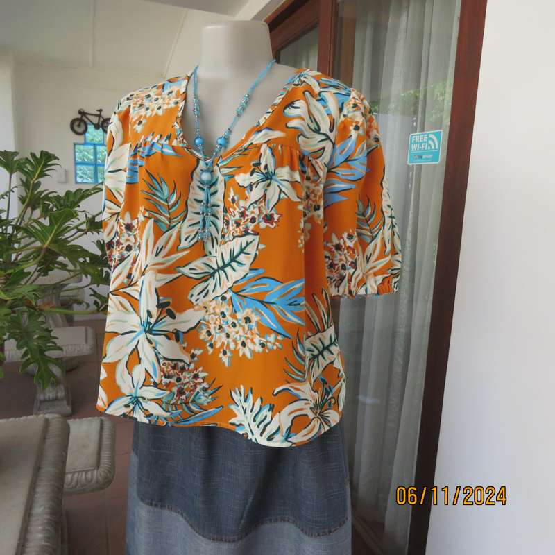 Eye catching slip over free hanging polyester top in burnt orange-blue and white flowers.Size 36.