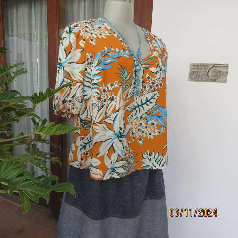 Eye catching slip over free hanging polyester top in burnt orange-blue and white flowers.Size 36.