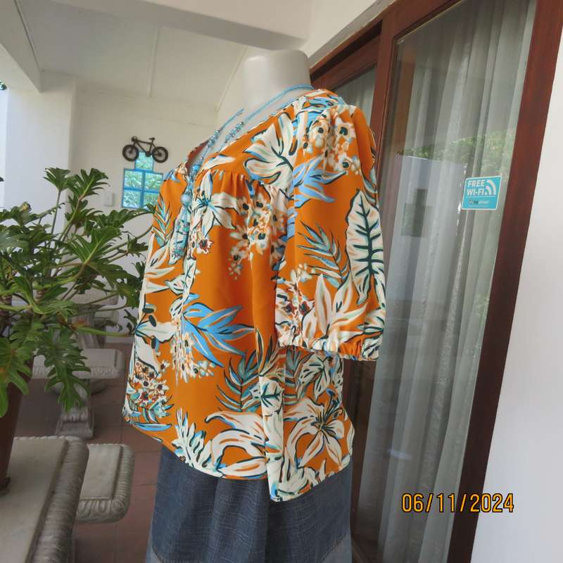 Eye catching slip over free hanging polyester top in burnt orange-blue and white flowers.Size 36.