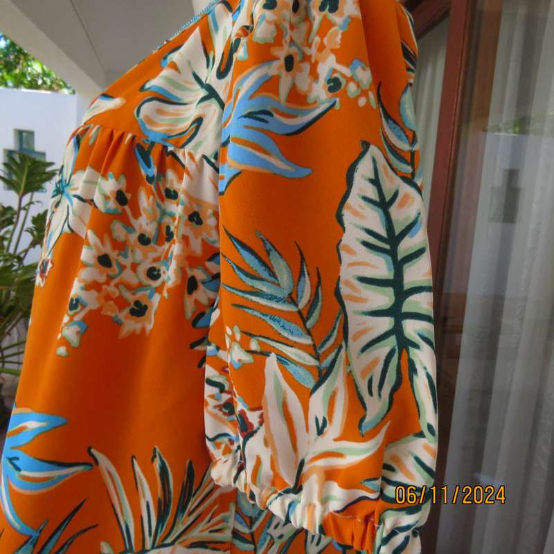 Eye catching slip over free hanging polyester top in burnt orange-blue and white flowers.Size 36.