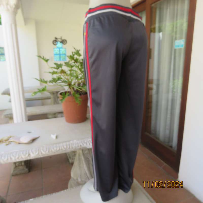 Steel grey track suit pants with wide stretch waistband in grey-red-silver. Size 38. Side stripes.