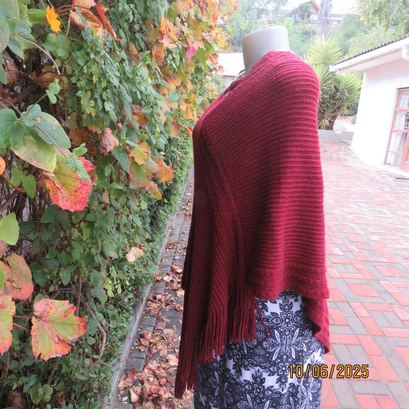 Maroon acrylic knit poncho partly fringed to fit size 32 to 36.