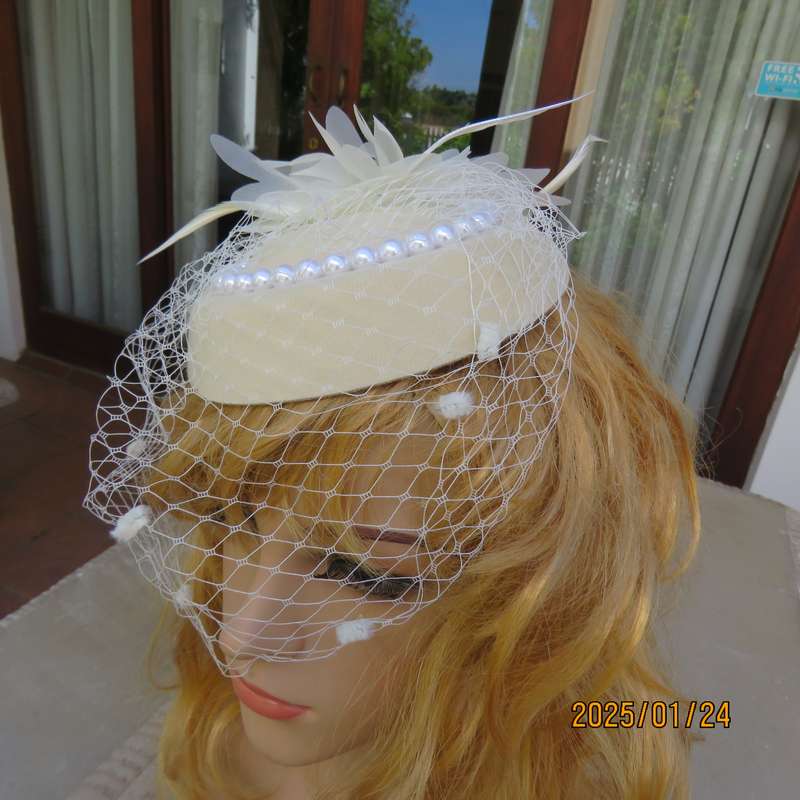 Fabulous little rich cream pillbox style fascinator with veil-pearl decoration and flower-feathers.