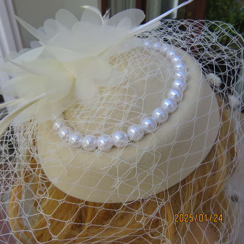 Fabulous little rich cream pillbox style fascinator with veil-pearl decoration and flower-feathers.
