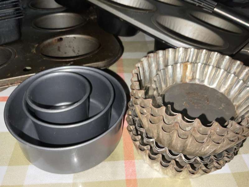 A selection of muffin baking trays, tart tins ,small cake tins and a large whisk.