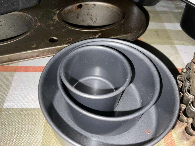 A selection of muffin baking trays, tart tins ,small cake tins and a large whisk.