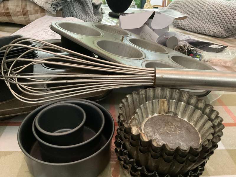 A selection of muffin baking trays, tart tins ,small cake tins and a large whisk.