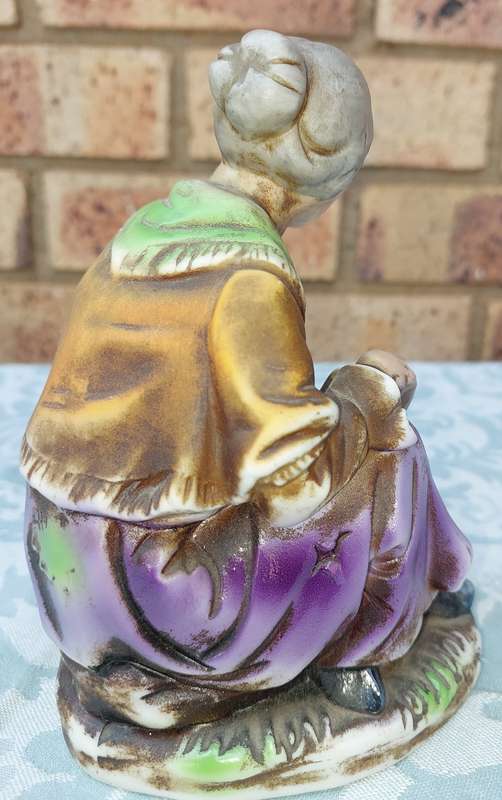 A VINTAGE CERAMIC  ELDERLY LADY SITTING AND HOLDING AN APPLE FIGURINE