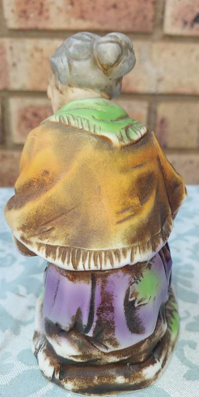 A VINTAGE CERAMIC  ELDERLY LADY SITTING AND HOLDING AN APPLE FIGURINE