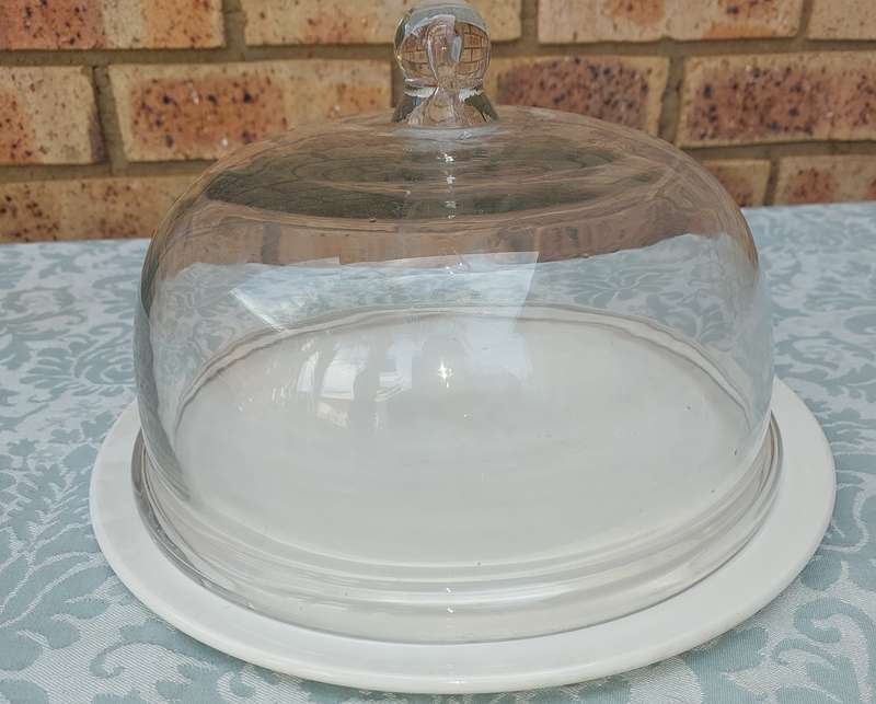 A WHITE PORCELAIN CAKE PLATE WITH A HEAVY GLASS DOME