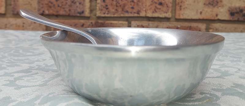 AN ALLOY ROUND SERVING BOWL WITH A LADEL SOLD AS IS
