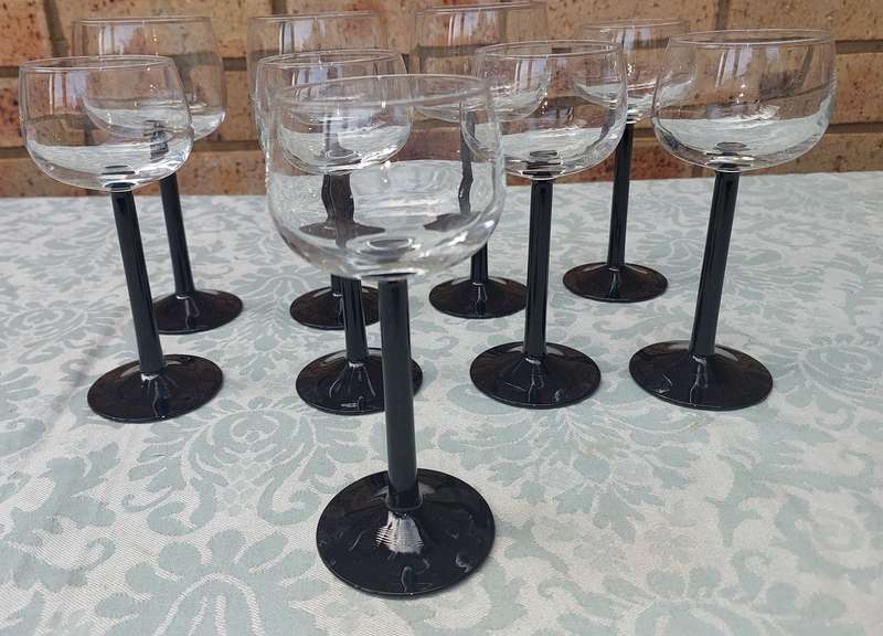 A SET OF 9 ART DECOR WINE GLASSES WITH BLACK STEMS SOLD AS IS