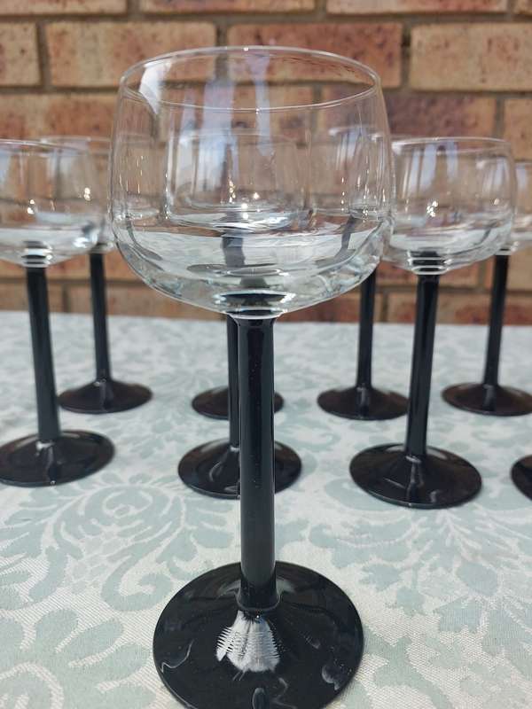 A SET OF 9 ART DECOR WINE GLASSES WITH BLACK STEMS SOLD AS IS
