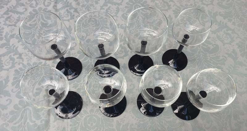 A SET OF 9 ART DECOR WINE GLASSES WITH BLACK STEMS SOLD AS IS