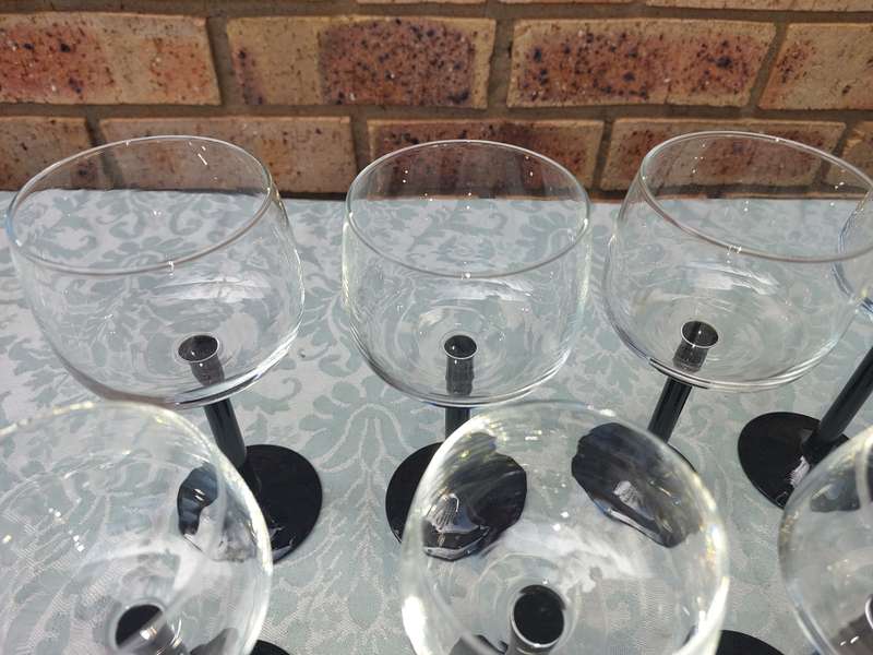 A SET OF 9 ART DECOR WINE GLASSES WITH BLACK STEMS SOLD AS IS