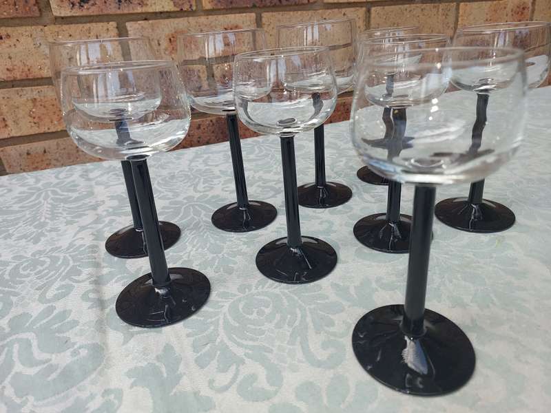A SET OF 9 ART DECOR WINE GLASSES WITH BLACK STEMS SOLD AS IS