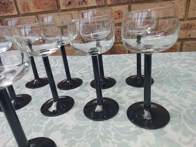 A SET OF 9 ART DECOR WINE GLASSES WITH BLACK STEMS SOLD AS IS