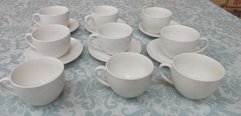 A COLLECTION OF 9 WHITE PORCELAIN TEACUPS AND 6 SAUCERS  SOLD AS IS