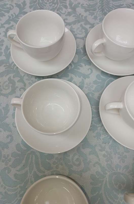 A COLLECTION OF 9 WHITE PORCELAIN TEACUPS AND 6 SAUCERS  SOLD AS IS