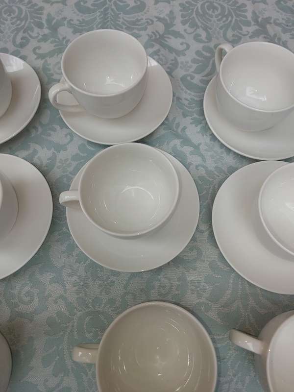 A COLLECTION OF 9 WHITE PORCELAIN TEACUPS AND 6 SAUCERS  SOLD AS IS