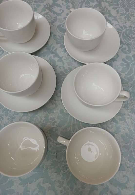 A COLLECTION OF 9 WHITE PORCELAIN TEACUPS AND 6 SAUCERS  SOLD AS IS