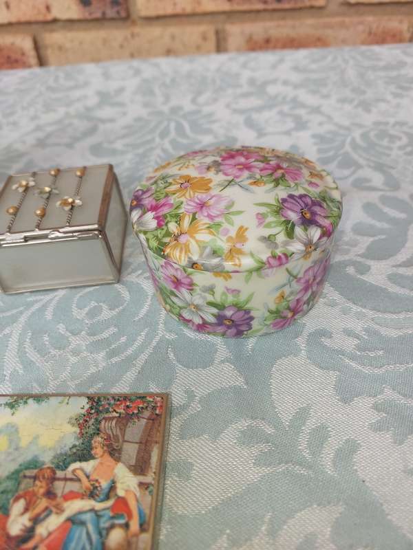 A VINTAGE COLLECTION OF TRINKETS , POCKET MIRRORS AND FIGURINES SOLD AS IS