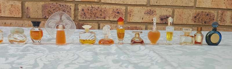 A COLLECTION OF MINITURE LALIQUE PERFUME BOTTLES AND SOME HAVE PERFUMES IN IT SOLD AS IS