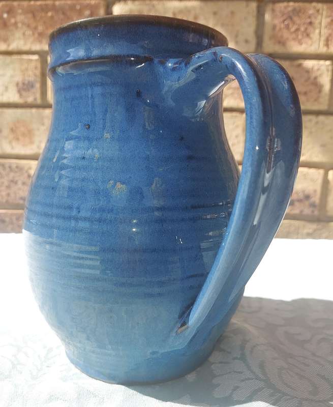A VINTAGE CERAMIC BLUE GLAZED WATER JUG SOLD AS IS