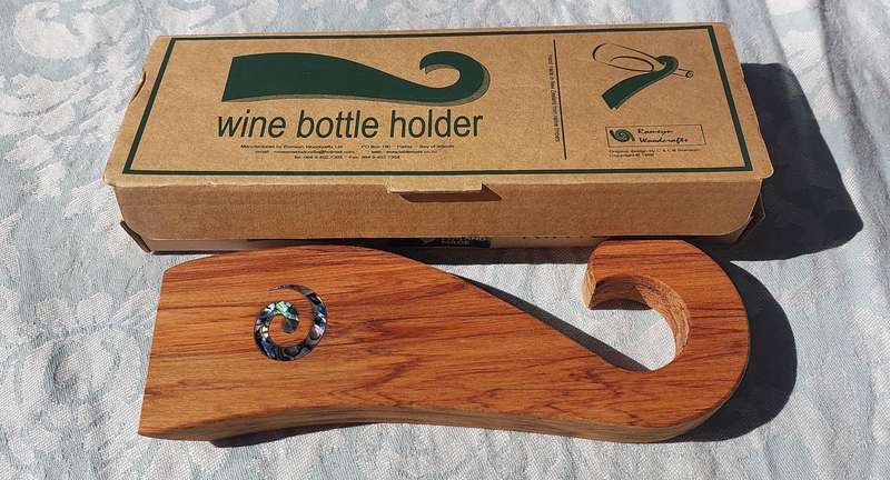 A WOODEN WINE HOLDER MADE IN NEW ZEALAND WITH MOTHER IF PEARL INLAY SOLD AS IS