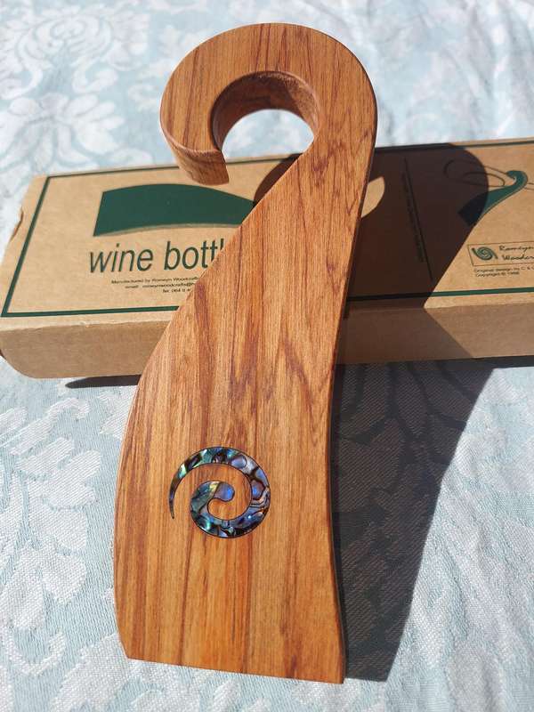 A WOODEN WINE HOLDER MADE IN NEW ZEALAND WITH MOTHER IF PEARL INLAY SOLD AS IS