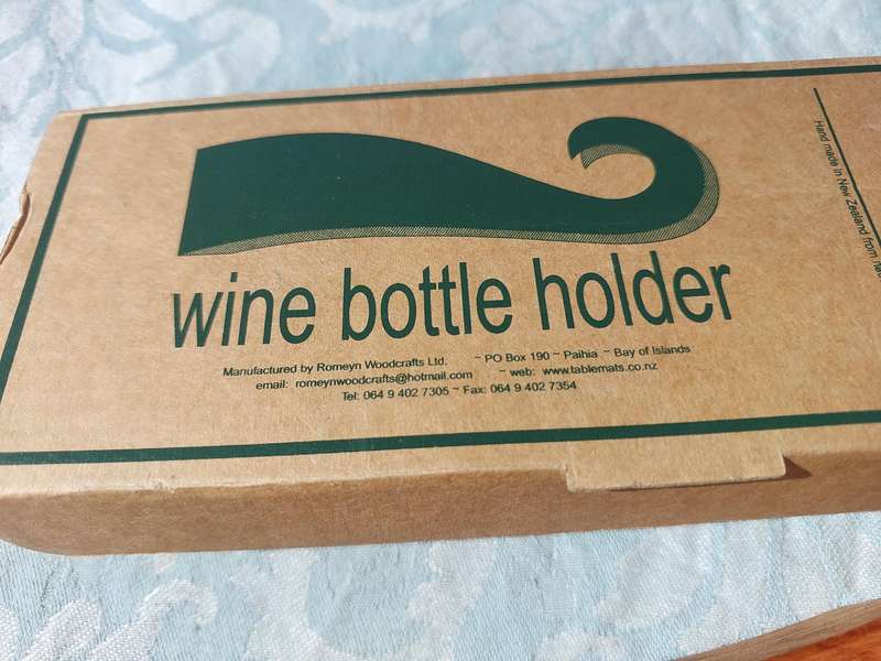 A WOODEN WINE HOLDER MADE IN NEW ZEALAND WITH MOTHER IF PEARL INLAY SOLD AS IS