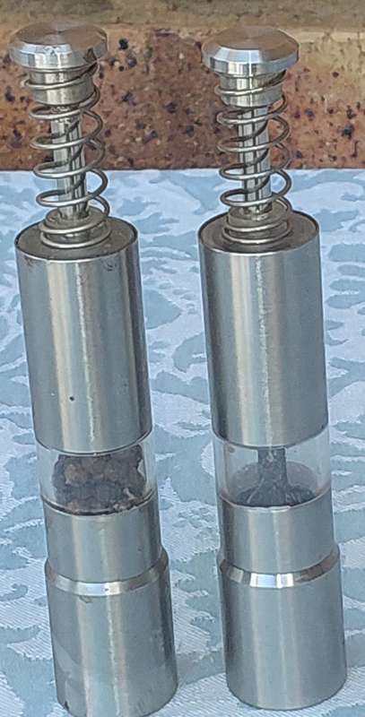 A SET OF STAINLESS STEEL PLUNGER SALT AND PEPPER DISPENSERS