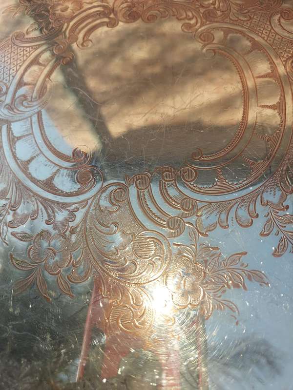AN ANTIQUE ENGRAVED VICTORIAN FOOTED ROUND SILVER ON COPPER SERVING TRAY SOLD AS IS