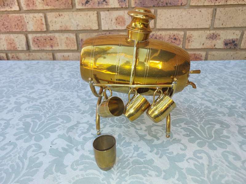 A VINTAGE HEBREW WINE DECANTER AND SIX CUPS BRASS ON A STAND ONE CUP NEED THE HANDLE TO BE ATTACHED