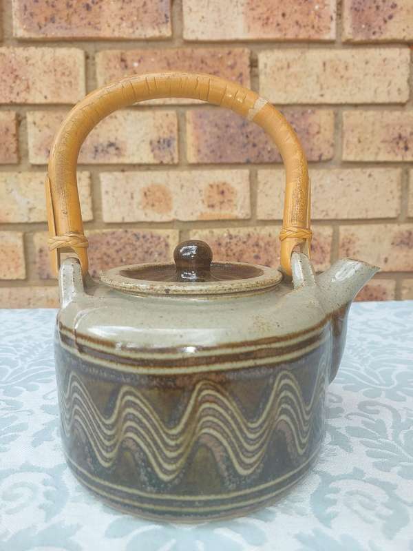A BAKED CLAY CERAMIC TEAPOT WITH A BAMBOO HANDLE SOLD AS IS