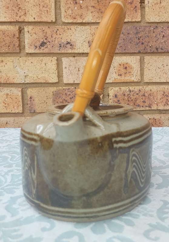 A BAKED CLAY CERAMIC TEAPOT WITH A BAMBOO HANDLE SOLD AS IS
