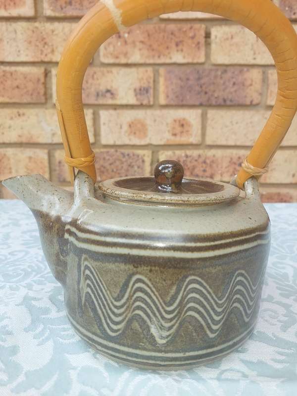 A BAKED CLAY CERAMIC TEAPOT WITH A BAMBOO HANDLE SOLD AS IS