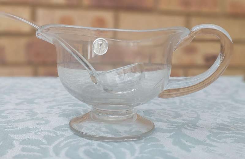 A CUT GLASS SAUCE JUG AND LADLE MADE IN ROMANIA SOLD AS IS