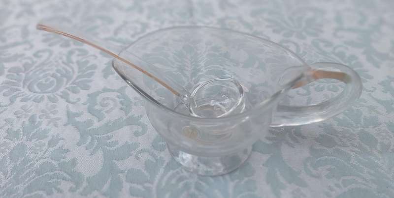 A CUT GLASS SAUCE JUG AND LADLE MADE IN ROMANIA SOLD AS IS