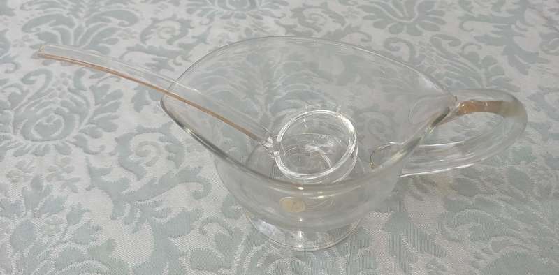 A CUT GLASS SAUCE JUG AND LADLE MADE IN ROMANIA SOLD AS IS